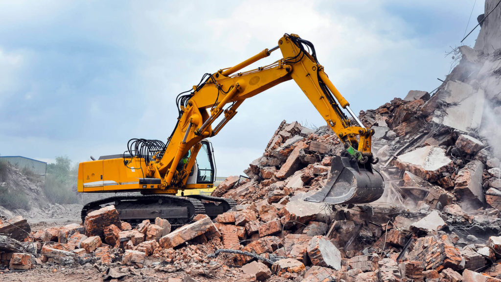 An excavator demolishing a concrete building.