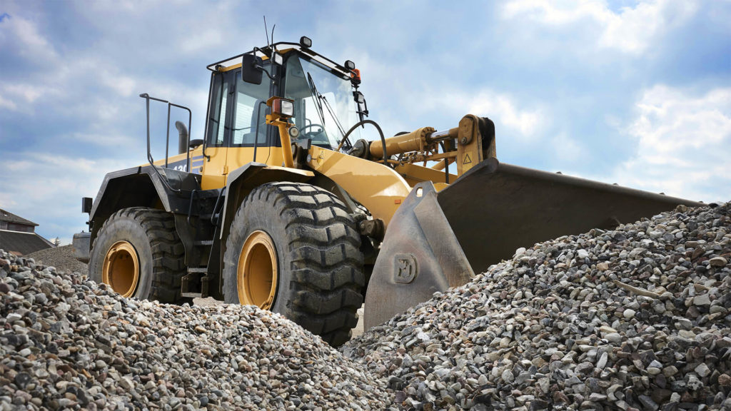 A loader behind a pile of gravel.