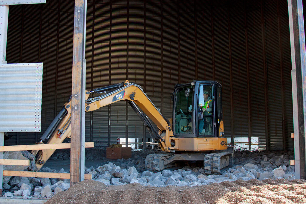 Mini excavator demolishing grain bin floor at FWS site.