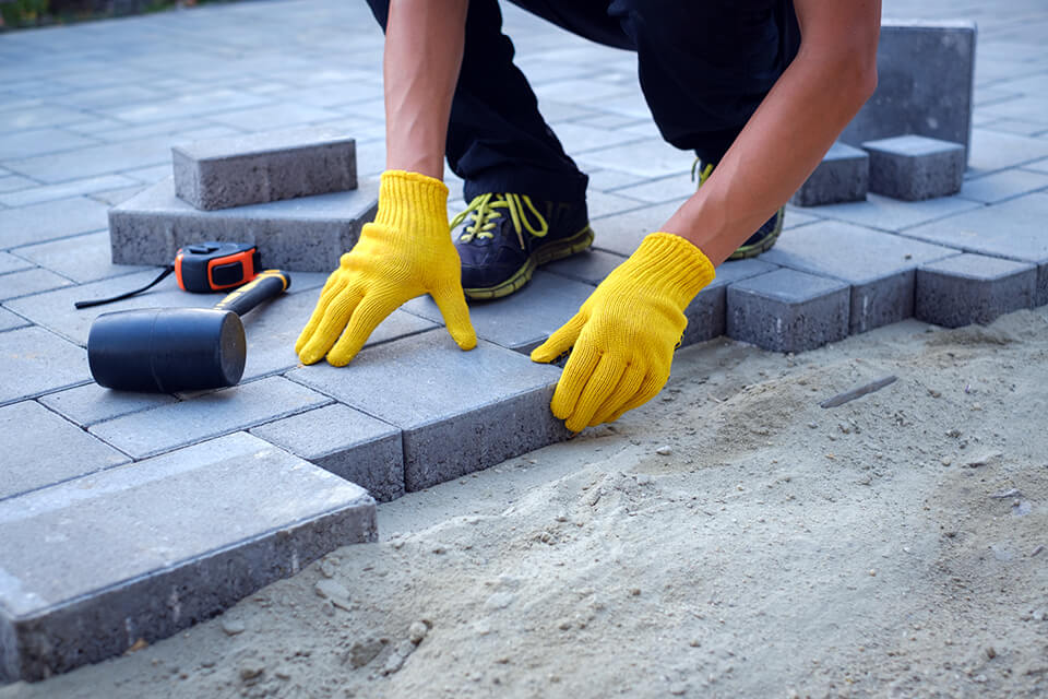 A brick pathway being paved over fill sand.