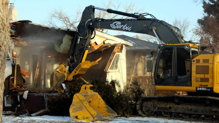 An excavator demolishing a house in Regina.