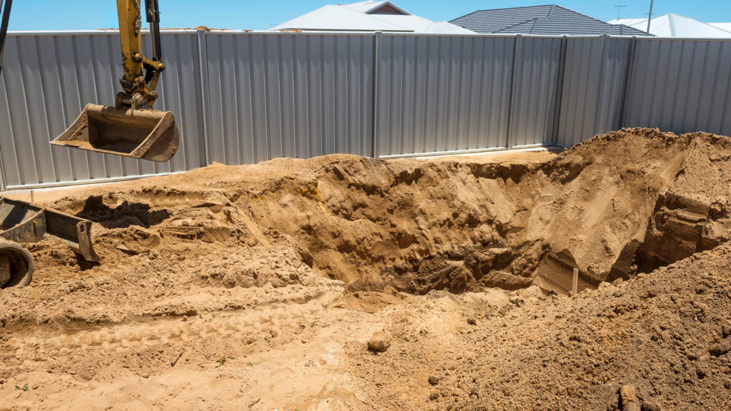 An excavator digging a hole in a backyard..