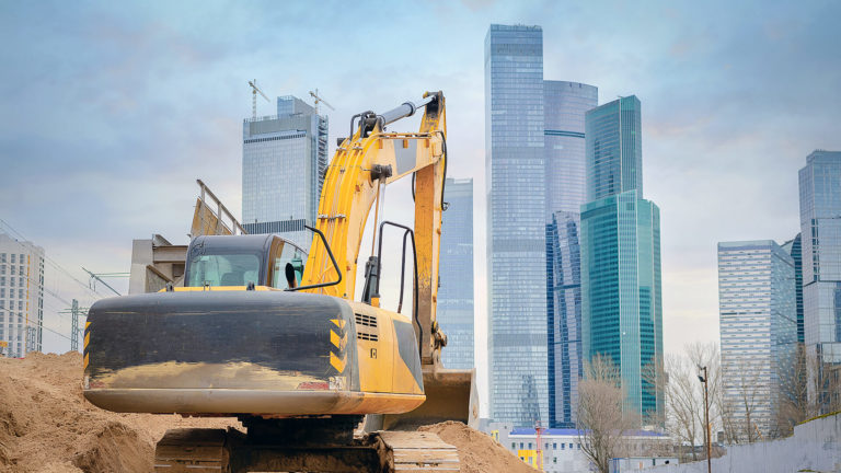 Commercial buildings behind an excavator.