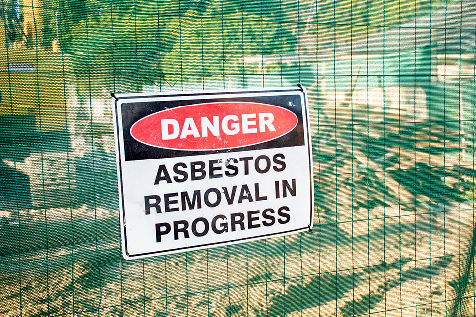 Asbestos in progress sign displayed during demolition.