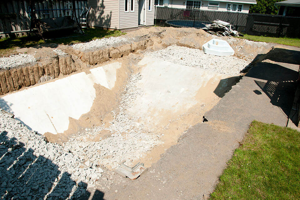 A hole excavated for a large pool in a backyard.