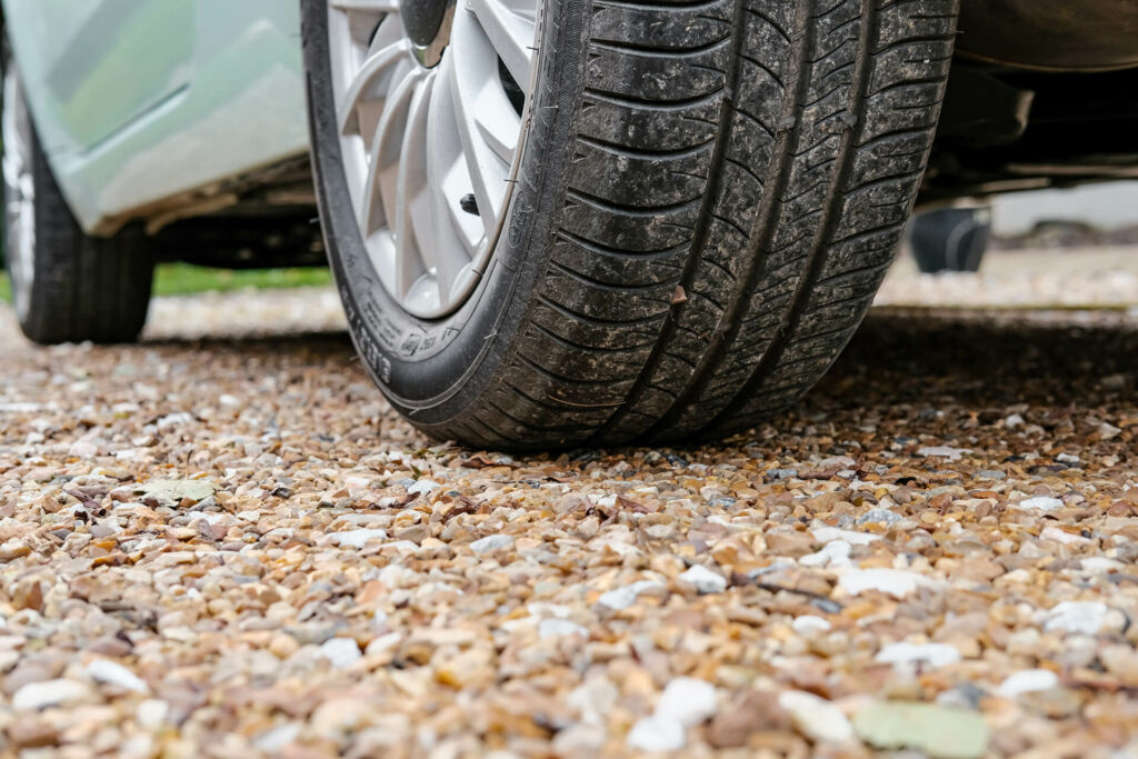 Car parked on top of a gravel driveway.