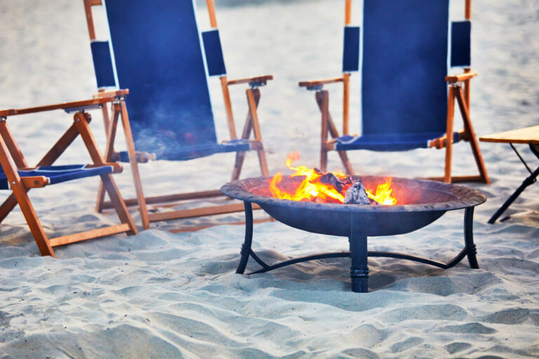Fire pit and loungers on a beach.