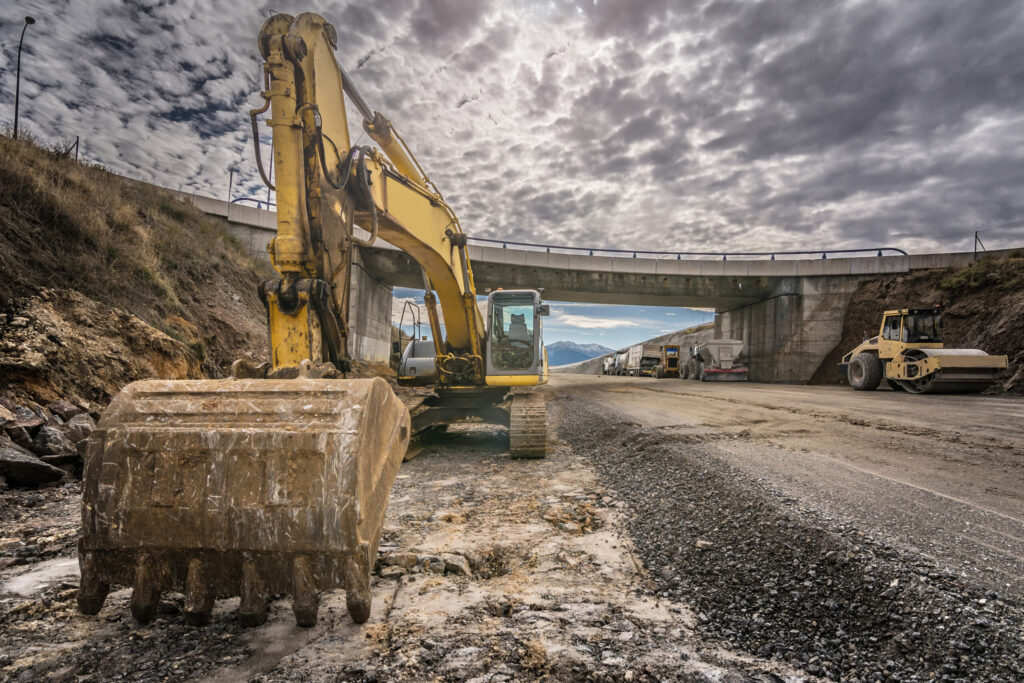 Excavator parked at a roadway project site.