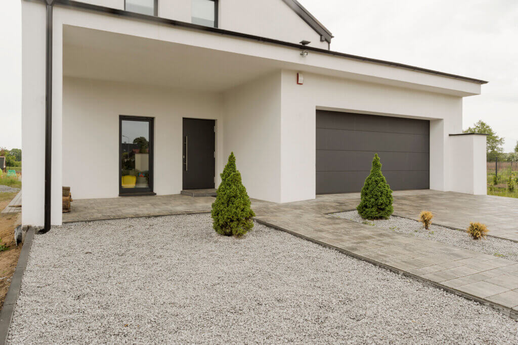 Residential home with a clean gravel parking area next to a driveway and garage.