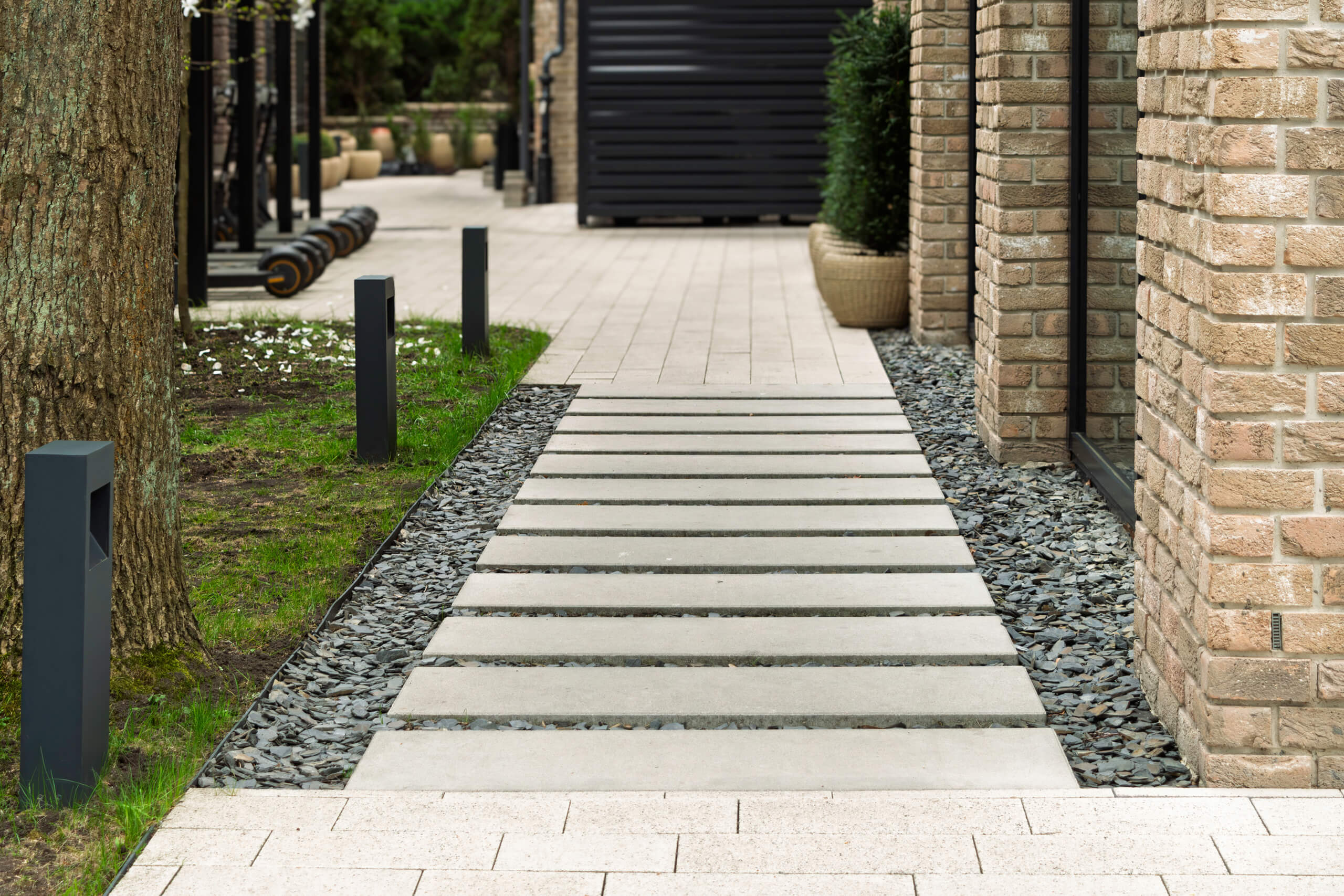 Irregular flagstone stepping stones set flush in a white pea gravel path beside lush garden plants.